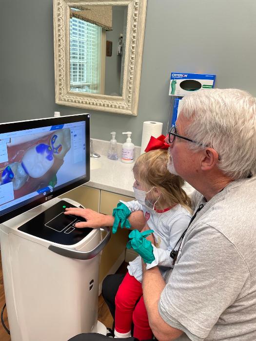 dr. booth with young patient looking at dental impression